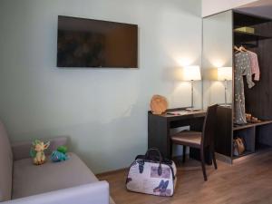 a room with a bed and a desk with a bag at ibis Styles Beaulieu sur Mer in Beaulieu-sur-Mer