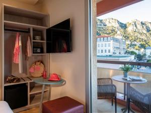 a room with a table and a balcony with a view at ibis Styles Beaulieu sur Mer in Beaulieu-sur-Mer