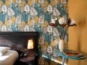 a bedroom with a bed and a table with a vase of flowers at ibis Styles Beaulieu sur Mer in Beaulieu-sur-Mer