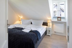 a bedroom with a bed with white pillows and a window at Lister Kaiser in List
