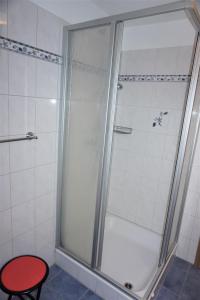 a shower with a red stool in a bathroom at Robbeninsel in Norden +15 photos