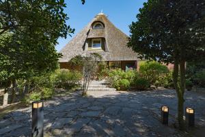 a house with a thatched roof in a yard at Fischers Koje in List