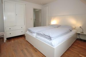 ein weißes Schlafzimmer mit einem Bett mit weißer Bettwäsche in der Unterkunft Olhörnweg 2 in Wyk auf Föhr