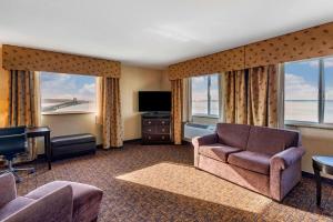 a hotel room with a couch and a tv and windows at Lloyd Hotel Astoria Bayfront, Ascend Hotel Collection in Astoria, Oregon