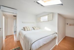 Dormitorio blanco con cama y tragaluz en Bright Apt w Balcony, AC, Parking, By TimeCooler, en Lisboa