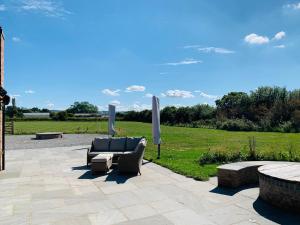 a patio with a couch and umbrellas and a field at Luxury Studio Cottage at Foot of Yorkshire Wolds in York