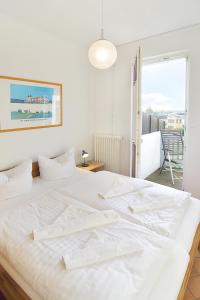ein weißes Bett in einem Zimmer mit einem großen Fenster in der Unterkunft Hamburg App. 05 in Ahlbeck