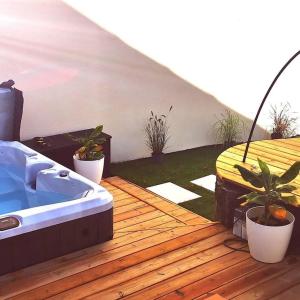 a hot tub on a wooden deck with potted plants at Ô'date gîte &spa in Nantes