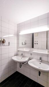 シュヴァンガウにあるFerienwohnung Eichhornの白いタイル張りの壁のバスルーム(シンク2台付)
