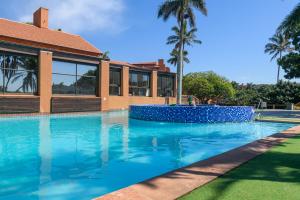 uma piscina em frente a uma casa com palmeiras em San Lameer Villa 3207 - 3 Bedroom Superior - 6 pax - San Lameer Rental Agency em Southbroom