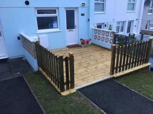 a wooden deck in front of a house with a dog at 34 Surfview Beach House in Newquay