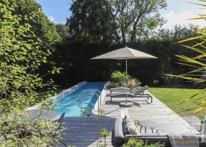 a swimming pool with an umbrella and some chairs and a patio at Maison de la Vicomté in Dinard