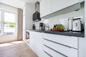 a kitchen with white cabinets and a counter with fruits and vegetables at Villa Zweite Heimat - Exklusive Penthouse No 4 in Lohme