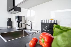 a kitchen counter with a sink and some tomatoes at Villa Zweite Heimat - Exklusive Penthouse No 4 in Lohme