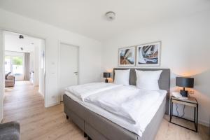 a white bedroom with a large bed and two lamps at Villa Zweite Heimat - Exklusive Penthouse No 4 in Lohme +10 photos