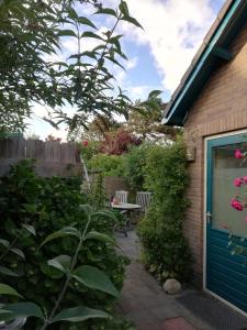 un jardín con una mesa y una puerta azul en Cottage Egmond-Binnen met besloten tuin, en Egmond-Binnen