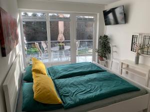 a bedroom with a bed with a green and yellow pillow at Ferienwohnung Nordseebrandung A2.5 in Sahlenburg