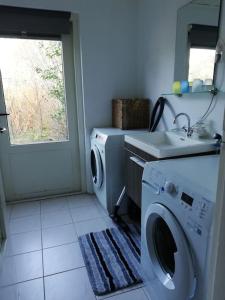 una lavanderia con lavatrice e lavandino di Cottage Egmond-Binnen met besloten tuin a Egmond-Binnen