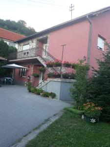 a pink building with a balcony and flowers on it at Apartman Drina in Berilovac