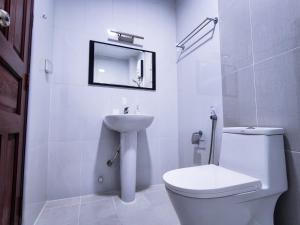 een witte badkamer met een toilet en een wastafel bij Reef Guest House in Male City