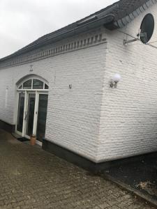 een wit bakstenen gebouw met een deur erop bij Kranenbruch in Schwalmtal