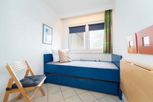 Un pequeño dormitorio con una cama azul y una silla en Berolina Wohnung 706, en Dahme