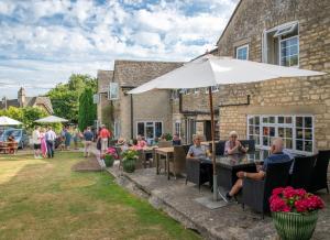 a group of people sitting at tables under an umbrella at Pettifers Freehouse Hotel in Crudwell