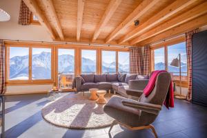 a living room with a couch and chairs and windows at Chalet Elsa in Riederalp
