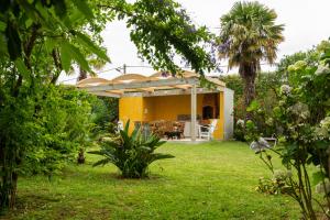 a garden with a yellow house with a patio at Quinta do Paraizo in Ribeira Grande
