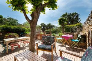 eine Terrasse mit einem Tisch, Stühlen und einem Baum in der Unterkunft La Calade in Montouliers