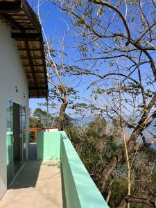 una casa con un porche verde y un árbol en Casa no Sul da Ilha, en Ilhabela