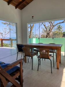 comedor con mesa, sillas y ventanas en Casa no Sul da Ilha, en Ilhabela