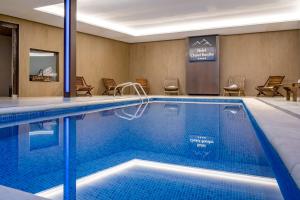 a pool in a hotel room with chairs and a table at Hotel Chalet Bassibe by Silken in Baqueira-Beret