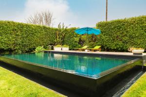 a swimming pool with a blue umbrella and a bench at Quinta do Paraizo in Ribeira Grande