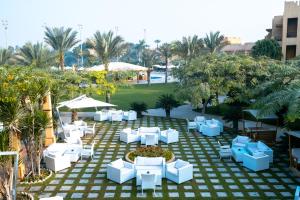 an outdoor patio with white furniture and palm trees at Swiss Inn Pyramids Golf Resort in 6th Of October