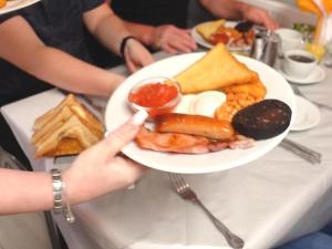una persona sosteniendo un plato de comida en una mesa en The Sandringham Court Hotel & Sports Bar-Groups Welcome here-High Speed Wi-Fi en Blackpool