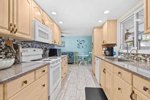 uma grande cozinha com armários de madeira e electrodomésticos brancos em Perfect for Family Gatherings with a Heated Pool! - Clearwater's Clear Choice em Clearwater