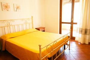 a bedroom with a bed with a yellow blanket at Mereu Central Apartment in Villasimius