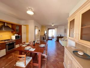 cocina y sala de estar con mesa de madera y sillas en Mereu Central Apartment, en Villasimius