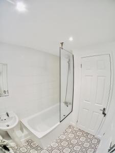 a white bathroom with a shower and a toilet and a sink at Private Parking Stylish Great Location in Guildford