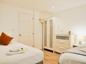 a white bedroom with two beds and a television at Private Parking Stylish Great Location in Guildford