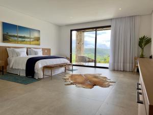 a bedroom with a bed and a large window at Lake Vilas Charm Hotel in Amparo