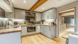 a kitchen with white cabinets and wooden floors at Church View Apartment in Stow on the Wold