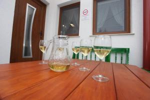 tres copas de vino blanco sentadas en una mesa de madera en Panorámás Vendégház, en Vértestolna