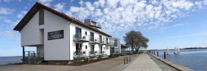 a white building next to a body of water at Hotel & Restaurant Utkiek in Greifswald