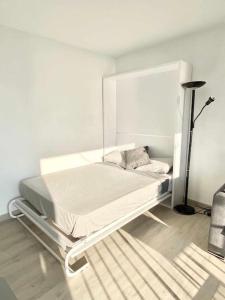 a white bed in a room with a lamp at Estudio Frente al Mar en Roses con Vistas in Roses
