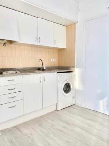 a kitchen with white cabinets and a washing machine at Estudio Frente al Mar en Roses con Vistas in Roses
