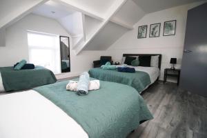 a bedroom with two beds with green sheets and a window at Executive Style 2 Bed Flat in Bridgend F2 in Bridgend