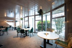 un restaurante con mesas, sillas y ventanas grandes en Hob Fort du Pré, en Saint-Bonnet-le-Froid