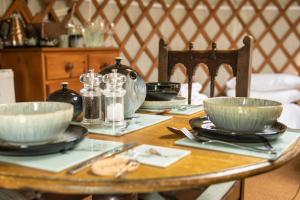 a wooden table with bowls and plates on it at Cherish Glamping in Askrigg